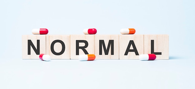 Normal word made on wooden cube blocks and pills