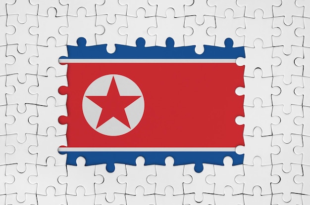 Фото Флаг северной кореи в рамке из белых кусочков головоломки с отсутствующей центральной частью