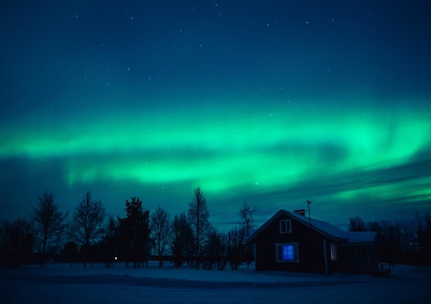 Northern lights Aurora Borealis over snowedin cottage in Lapland village Finland