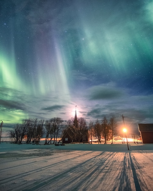 Aurora boreale sopra la chiesa cristiana con la luna