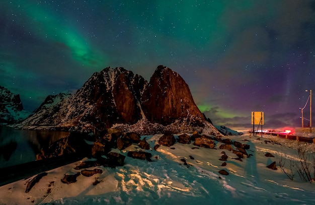 Northern lights over the mountains and fishing huts in the village of Hamnoy in Lofoten Islands