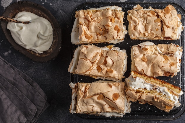 Norwegian Cake with meringue and whipped cream, dark background, top view.