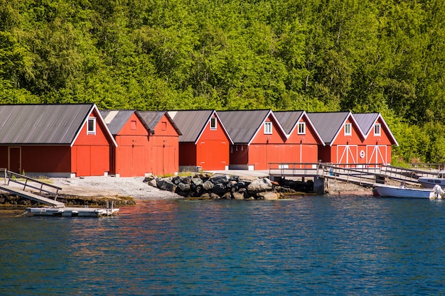 赤い家とノルウェーの漁船とノルウェーのフィヨルドの風景を見る。