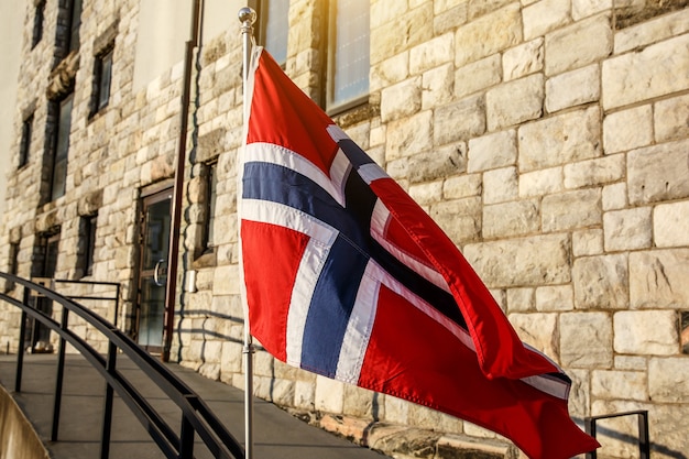 Foto bandiera norvegese, muro di mattoni di casa