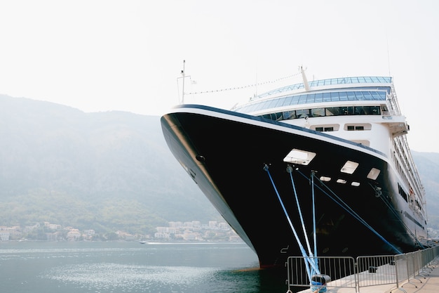 The nose of a closeup cruise liner moored on a jetty near the old town of kotor in montenegro in the