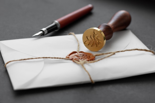 Notary public wax stamper. White envelope with brown wax seal, golden stamp. Still life with postal accessories.