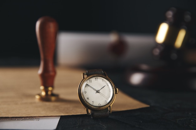 Notary stamp and wooden gavel with watch on the table