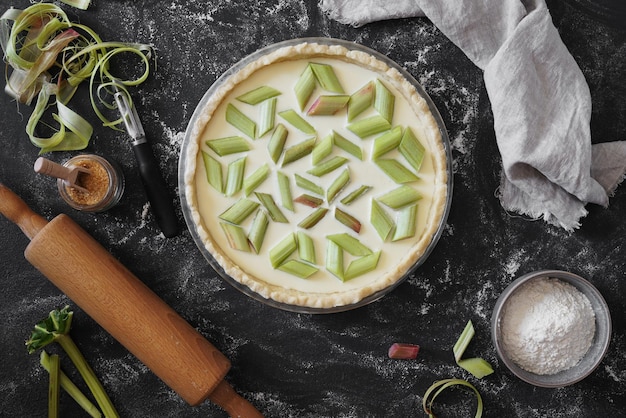 Notbaked Homemade Rabarber Pie op een donkere tafel met ingrediënten en platliggende close-up