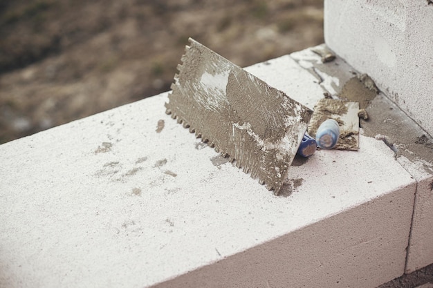 Notched trowel with cement on autoclaved aerated concrete blocks process of house building