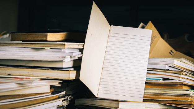 Note book with Stack of old books on wooden table.