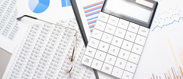 Note pad, pen, glasses and pocket calculator on a white surface