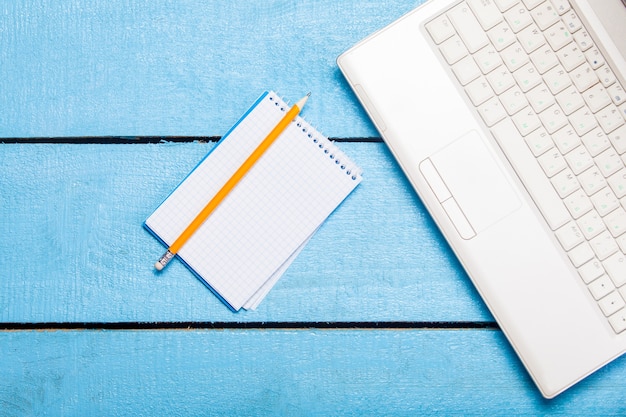 Note and white laptop computer on blue wood