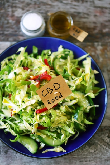 A note with the words cbd food in a plate with vegetable salad.