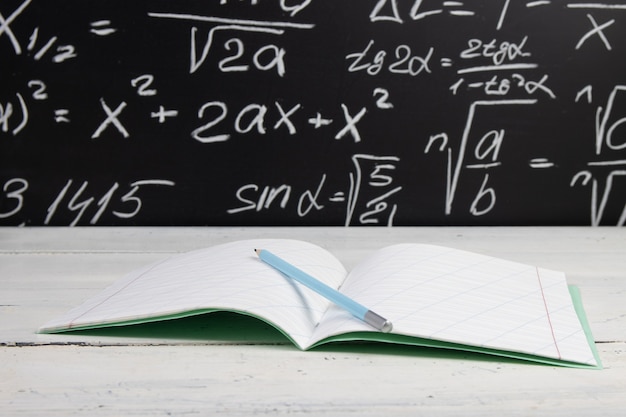 Notebook on blackboard background with mathematical formulas