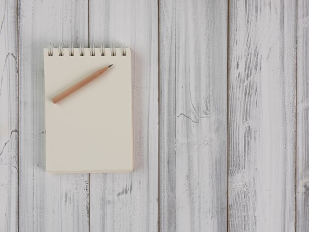 Notebook and brown pencil on wood table