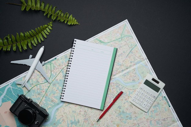 Notebook,camera,airplane,pen,calculator and map of traveler on black background with copy space .travel concept .