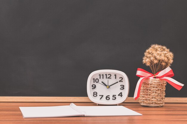 Photo the notebook and the clock are on the table.