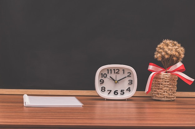 The notebook and the clock are on the table.