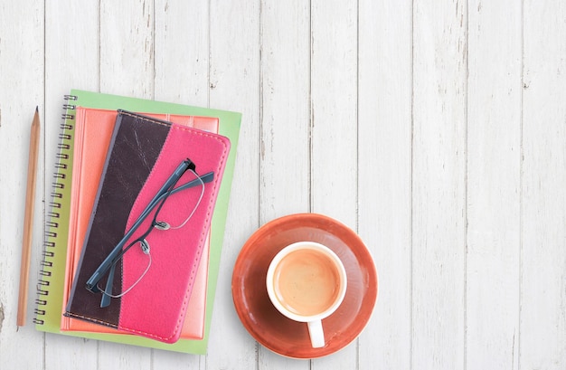 Notebook and coffee cup with pencil on white wooden