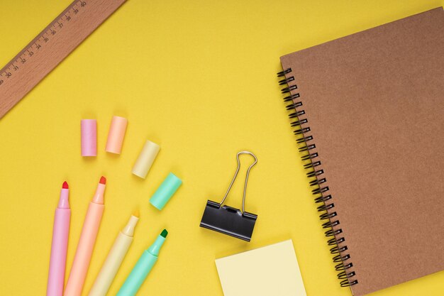 Notebook colored pencils note paper and clamp ruler back to school Isolated yellow background