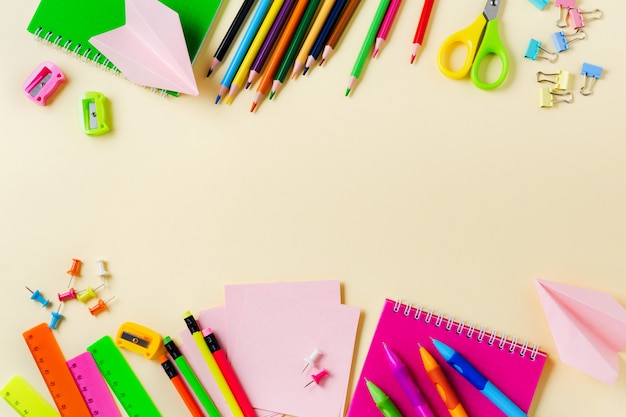 Notebook, colored pencils, ruler, pen, eraser, sharpener and school and office stationery on yellow background.