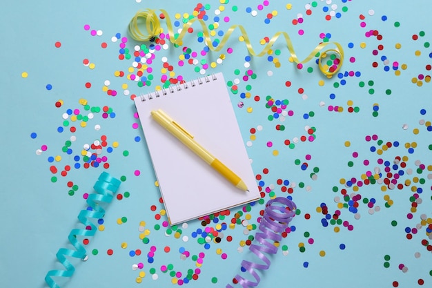 Notebook and confetti with streamer on blue background