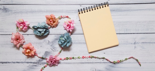 notebook decorated with multicolored flowers In the form of a heart on a wooden surface.