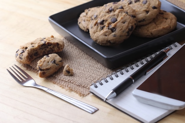 Notebook on desk with coffee biscuit and pen