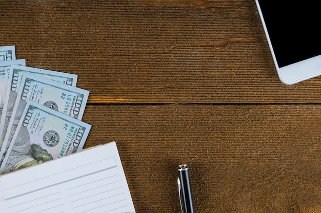 Photo notebook and dollars smart phone on wood