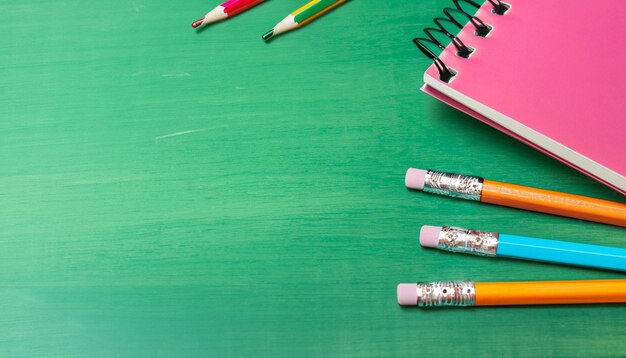Foto notebook en kleurrijke potloden op een tafel close-up groene bord achtergrond generatieve ai