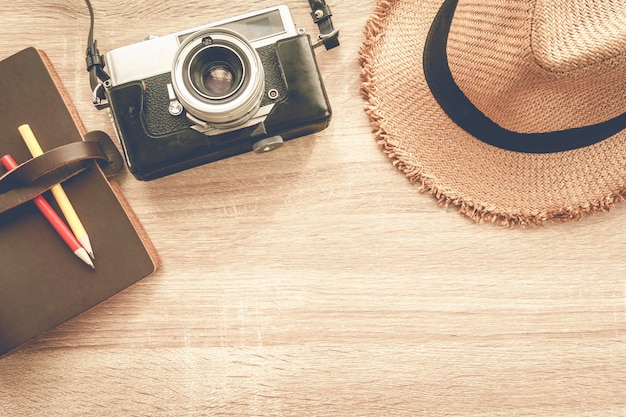 notebook film camera and wicker hat on wooden table