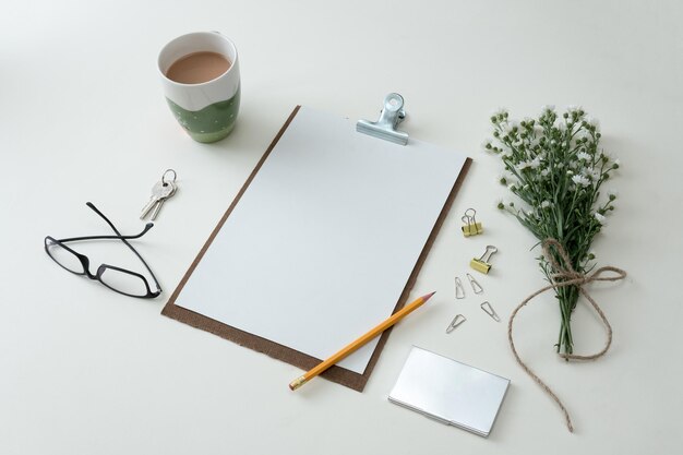 Notebook flat lay on white background with summer leaves and\
other stationery in trendy set up style