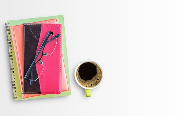 Notebook and glasses with cup of coffee on office desk