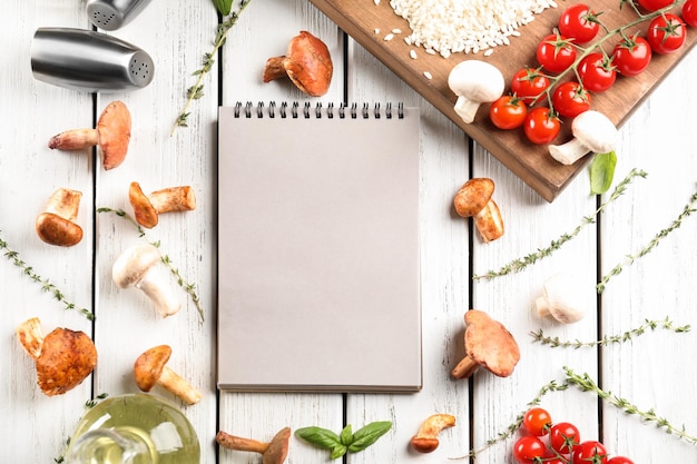 Photo notebook and ingredients for risotto with mushrooms on wooden background