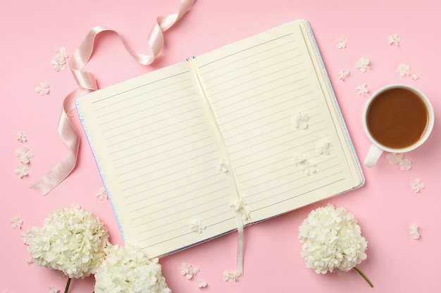 Notebook, koffie en hortensia bloemen op roze achtergrond