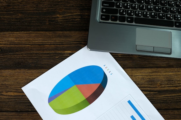 Notebook laptop computer and financial graph on white paper