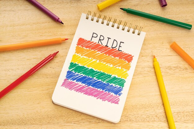 Foto notebook met lgbt regenboogvlag tekening en markerpennen op houten tafel