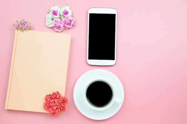 Notebook mobile phone and black coffee white cup pink background 