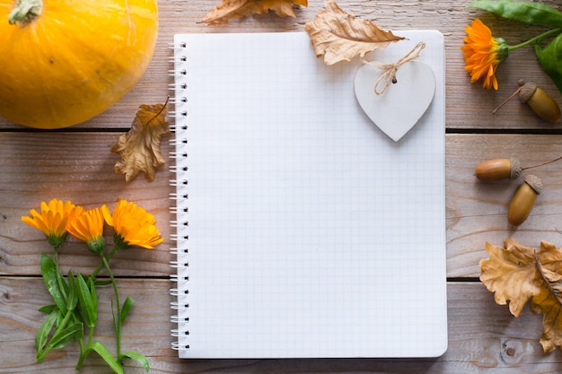 Notebook op houten herfst tafel met pompoen, bloemen droge bladeren