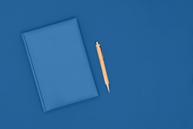 Notebook and pen on blue color. Business concept. Top view