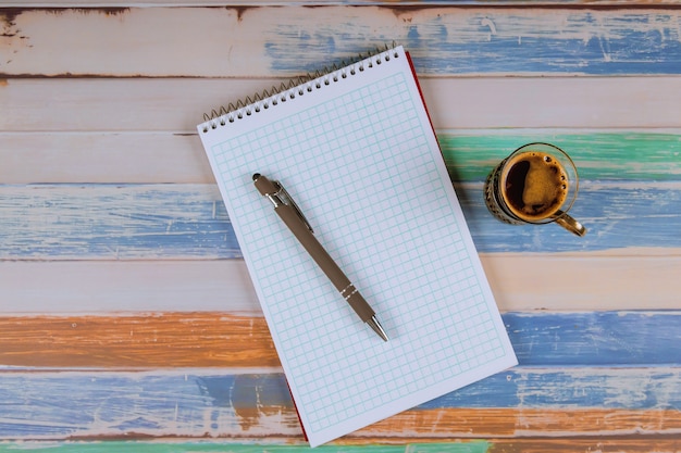 Notebook, pen en kopje koffie op tafel.