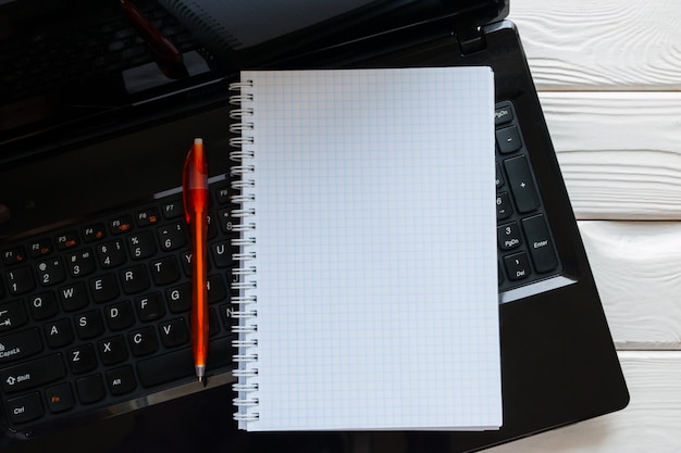 Notebook and pen lying on a laptop keyboard