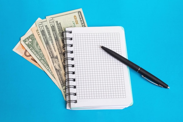 Notebook pen and money on a blue background