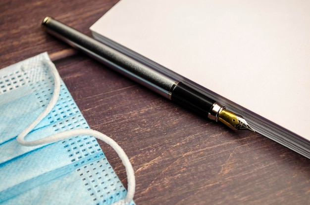 Notebook and pen for notes next to a medical protective mask