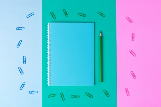 Photo notebook, pen, paper clip, on pastel blue, green, pink background. office desk with copy space. back to school.