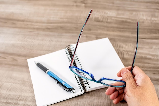 Photo notebook pen and reading glasses on wooden table