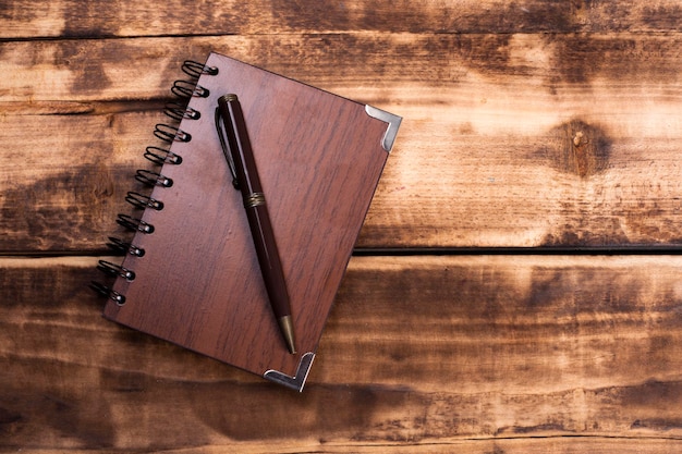 notebook and pen on wooden background