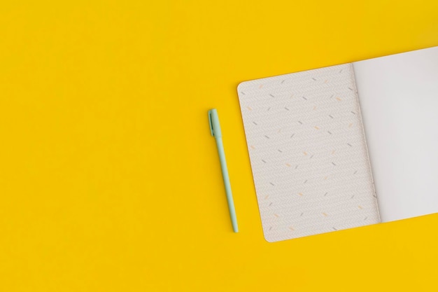 Notebook and pen on yellow background. Top view. Flat lay. Back to school concept.