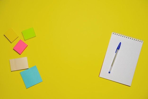 Notebook and pen on a yellow background top view with copy space stationery