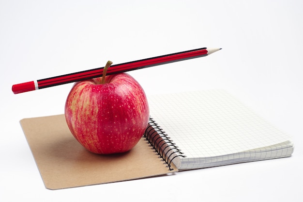 Notebook, pencil and apple on white background